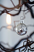 Silver Christmas bauble hanging from branch