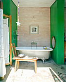 Frei stehende Badewanne zwischen grünen Wänden
