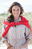 A young, long-haired woman wearing a beige linen blouse with a red jumper over her shoulder