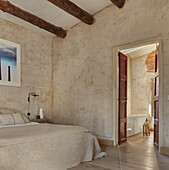 Double bed in the bedroom with sand colored walls and exposed wooden beams