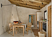 Dining area in front of brick fireplace and kitchenette in the room with sand-colored walls and reed ceiling