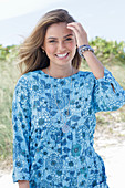 A young woman with long hair wearing a blue patterned dress