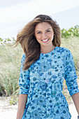 A young woman with long hair wearing a blue patterned dress