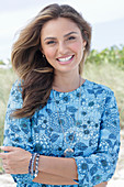 A young woman with long hair wearing a blue patterned dress