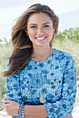 A young woman with long hair wearing a blue patterned dress