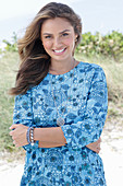 A young woman with long hair wearing a blue patterned dress