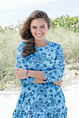 A young woman with long hair wearing a blue patterned dress