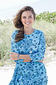 A young woman with long hair wearing a blue patterned dress