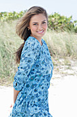 A young woman with long hair wearing a blue patterned dress