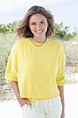 A young woman with long hair wearing a yellow jumper