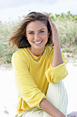 A young woman with long hair wearing a yellow jumper and trousers