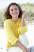 A young woman with long hair wearing a yellow jumper and trousers