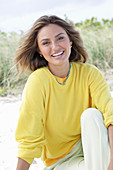 A young woman with long hair wearing a yellow jumper and trousers