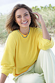 A young woman with long hair wearing a yellow jumper and trousers