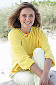 A young woman with long hair wearing a yellow jumper and trousers