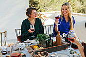 Frauen mit Rotwein am Tisch auf Terrasse