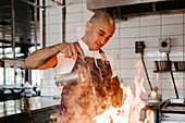 Koch in Restaurantküche kocht mit offenem Feuer