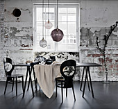 Schwarzer Tisch mit heller Tischdecke, Stühle und Glaskugellampen im Industrie-Ambiente