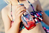 Mädchen trinkt am Strand aus Flasche