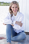 A long-haired blonde woman wearing a white shirt blouse and jeans