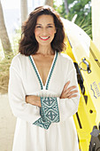 An older brunette woman wearing a white dress with a trim