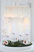 A tray with four white candles, Christmas baubles and fir sprigs