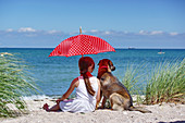 A girl with a parasol and a dog on the beach
