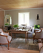 Gepolsterte Sessel, alter Holztisch und Sofa im Wohnzimmer mit grau-beiger Wand