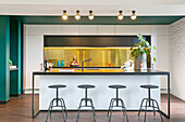 Kitchen island with bar stools, illuminated kitchen counter in the background