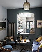 Gemütliches Wohnzimmer mit Polsterstühlen, Sofa und marokkanischen Tischlampen auf Coffeetable, Fenster zur Küche