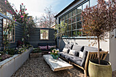 Cosy courtyard garden complete with mirrored windows and a sofa, the shiplap cladding is painted