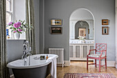 Black clawfoot bath with view through Georgian archway to mirror above double wash stand