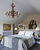 Half-wall headboard with mahogany tallboy, brass chandelier and table lamps