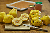 Quince jelly preparation with quince fruits and two pots on wood table