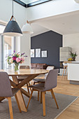 A round dining table with grey chairs in an open-plan living room