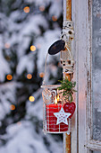 A Christmas lantern with a red candle hanging on a window