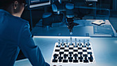 Engineer playing chess with a robotic arm