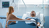 Wife sitting beside her husband's hospital bed