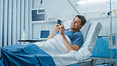 Recovering patient using a smartphone lying in bed