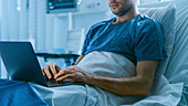 Recovering patient using a laptop in hospital