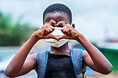 Girl in face mask making heart sign
