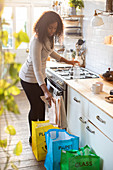 Woman recycling newspaper in kitchen