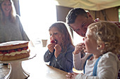 Family enjoying strawberry cake