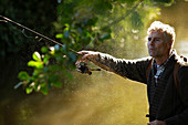 Man casting fly fishing pole into river