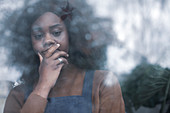 Sad woman with hand on chin at window