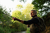 Man fly fishing with pole at riverbank