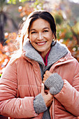 A dark-haired woman wearing a grey cardigan and a pink quilted jacket