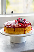 Lemon raspberry one layer cake on a cake stand on a window sill
