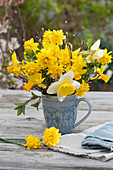 Spring bouquet of daffodils 'Tete Boucle', 'Goblet' and 'Jetfire' in a cup