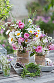 Early summer bouquets of roses, daisies, caraway, Canadian lilac, grass, hornwort, light carnation and cranesbill, grass wreath, and burlap ribbon